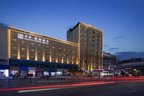 A multi-story hotel with a prominent signage, a covered entrance, and a parking area in front.