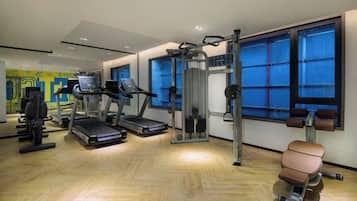 Une salle de sport équipée de tapis de course, d’appareils de musculation et d’un rameur.