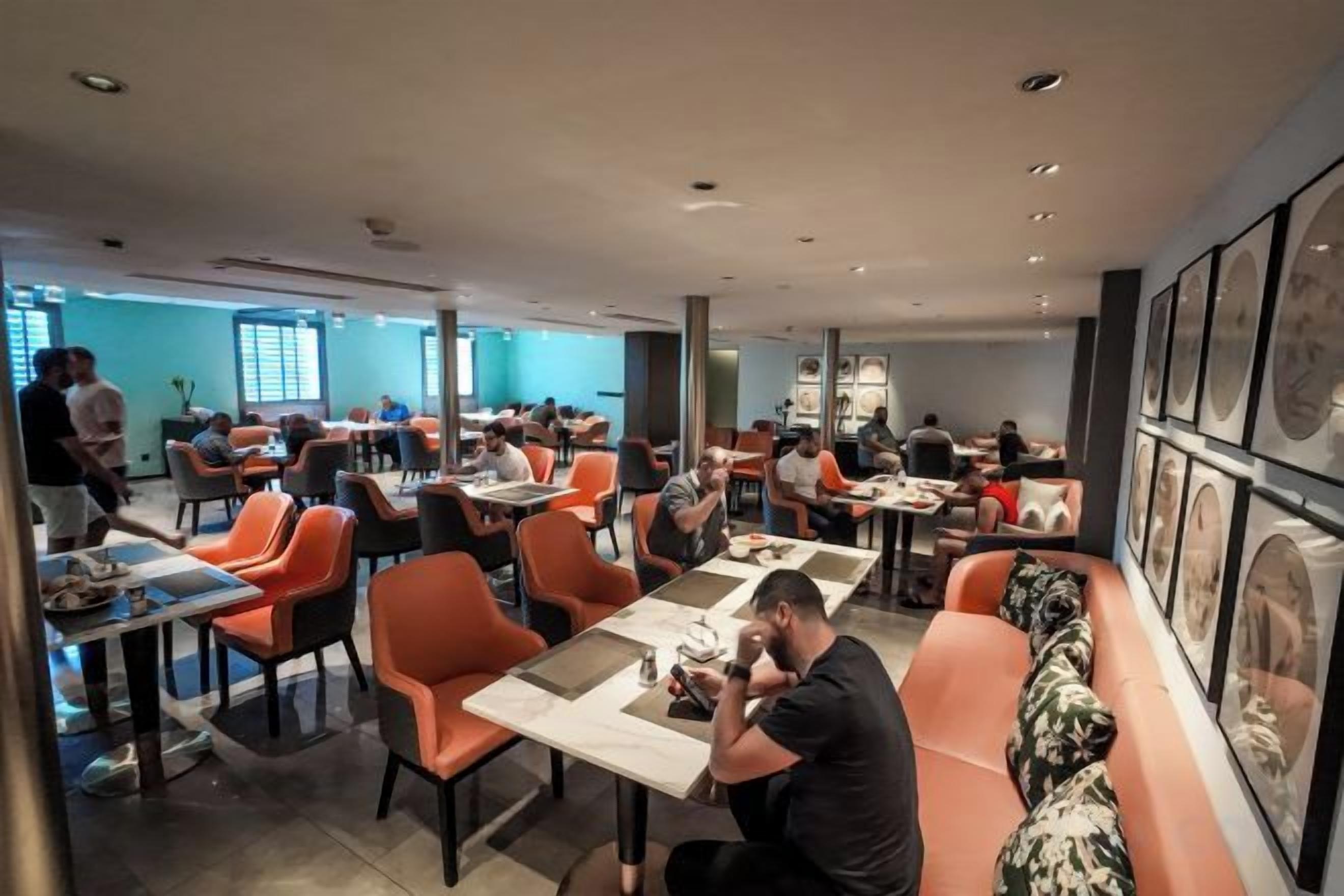 Un restaurant doté de nombreuses tables et chaises, d’un long comptoir et d’un espace salon avec un canapé.