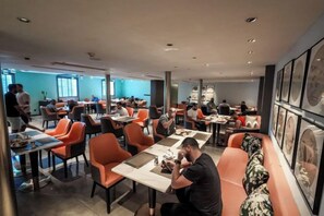 Un restaurant doté de nombreuses tables et chaises, d’un long comptoir et d’un espace salon avec un canapé.