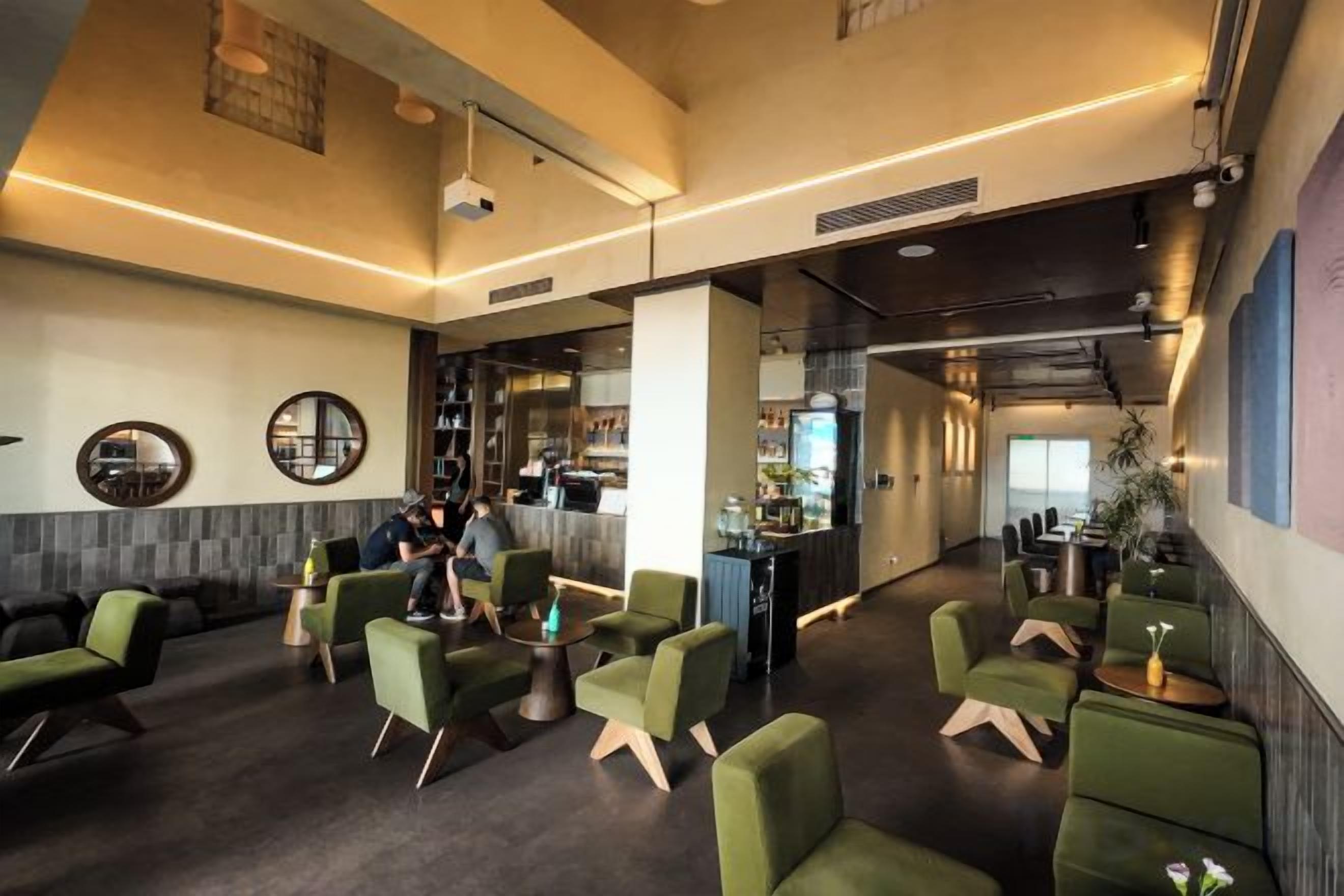 Un vestíbul modern amb seients verds, una zona de bar i vistes a la ciutat.