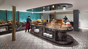 Un hall d’hôtel moderne avec un comptoir d’accueil incurvé, un espace bar et un sol à motifs.