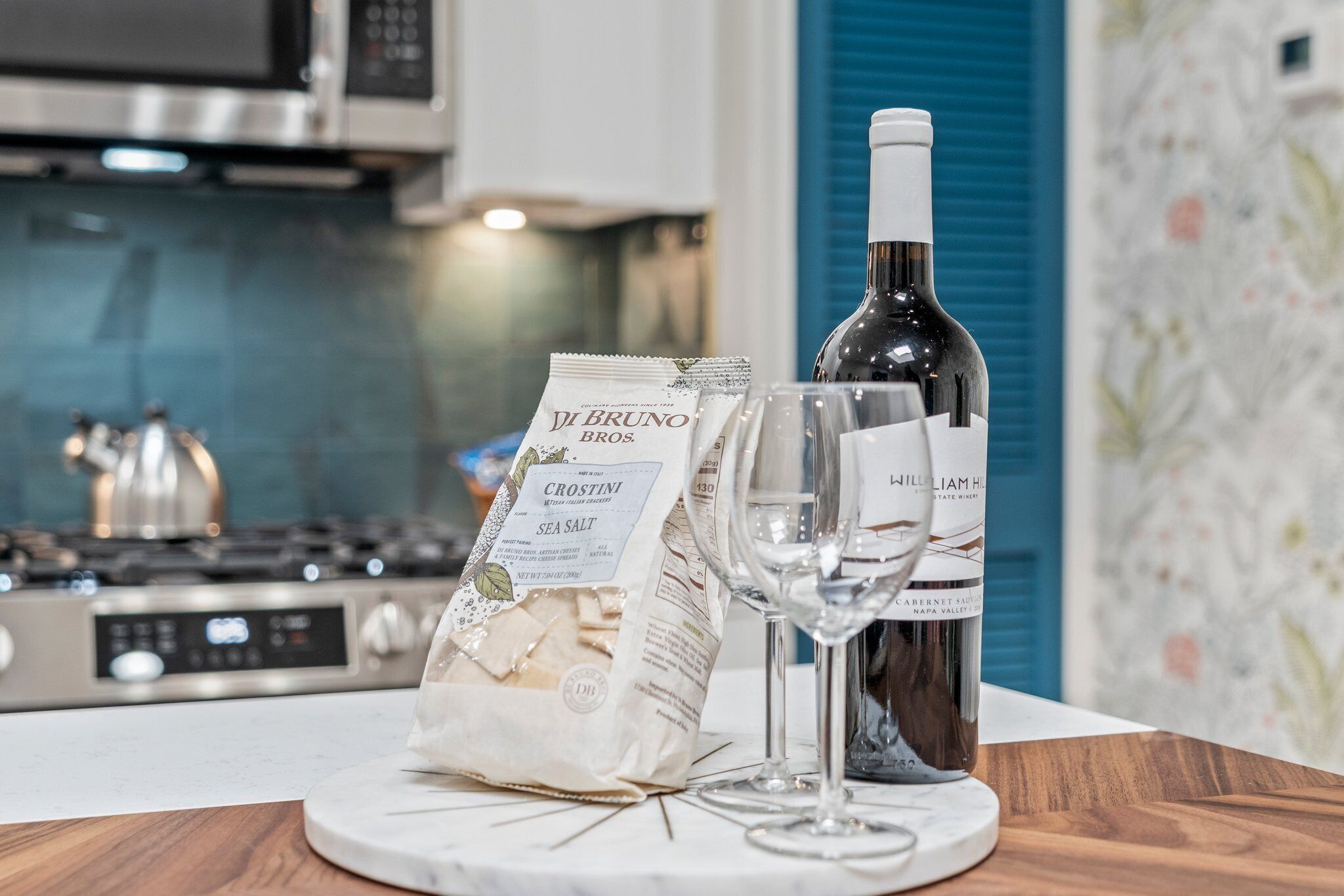 A kitchen counter with a bottle of wine, a glass, and a bag of sea salt.