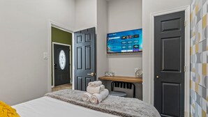 Una habitación de hotel moderna con cama, escritorio, televisor y puerta.