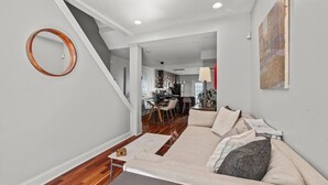 Ein modernes Wohnzimmer mit einer Couch, einem Couchtisch und einer Treppe, die in ein Obergeschoss führt.