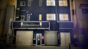 Ein zweistöckiges Gebäude mit dunkler Fassade und einem Schild mit der Aufschrift "Silhouette".