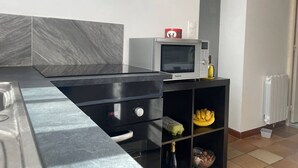 A modern kitchen with a black countertop, a microwave, and a small cabinet with bananas and eggs. - Charming house in the heart of the village (Bazouges-la-Pérouse)