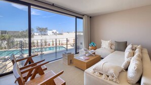 Una sala de estar moderna con un gran ventanal con vistas a una piscina y al paisaje urbano.
