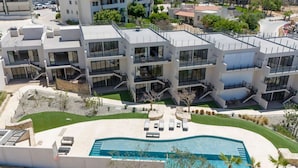 Un edificio moderno de varios pisos con piscina en la azotea y zona de estar al aire libre.