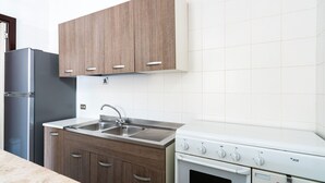 A kitchen with wooden cabinets, a stainless steel sink, a double oven, and a refrigerator. - 4163 Abate Filippo Home Holiday by Barbarhouse (Nardò)