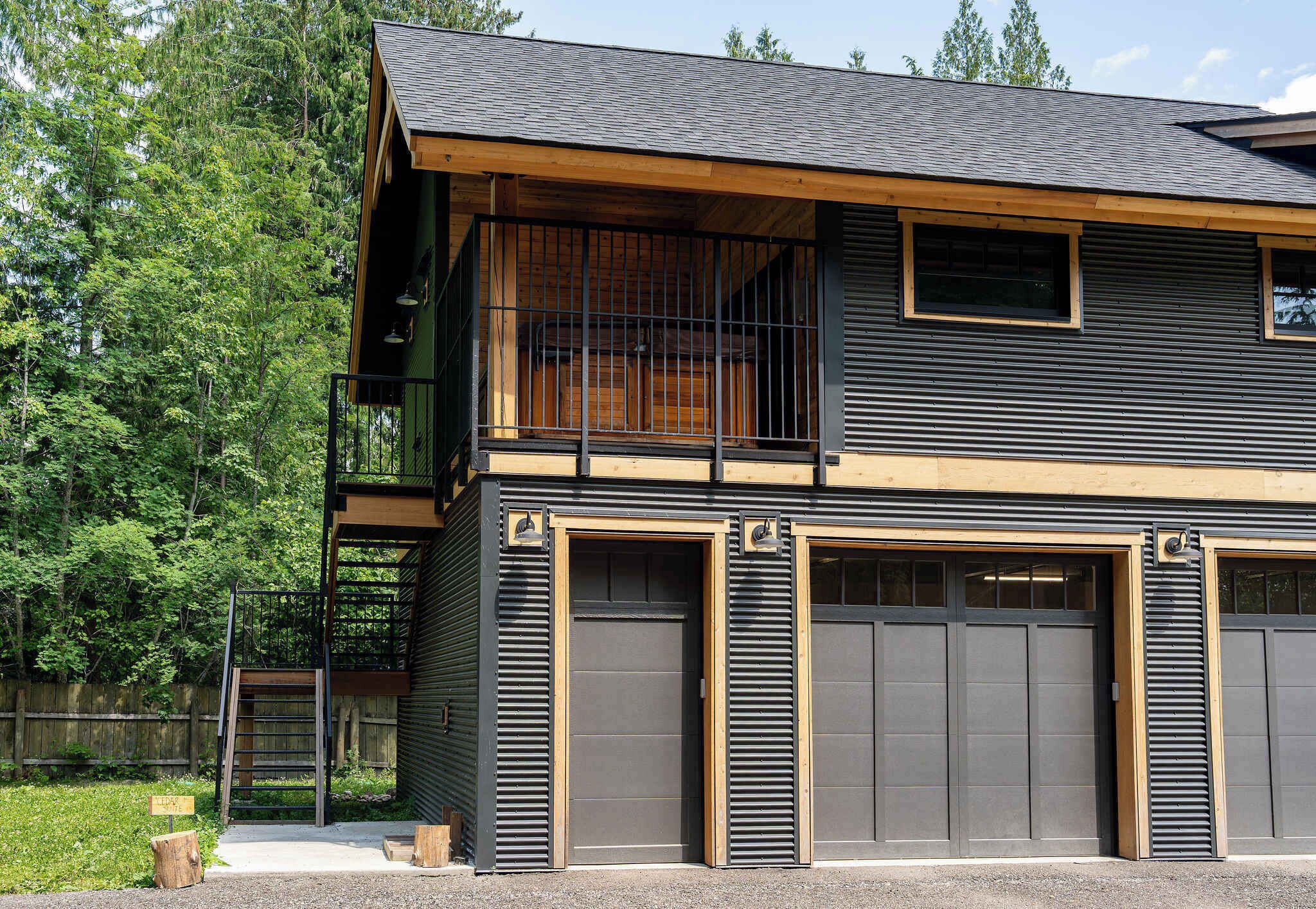 A two-story building with a balcony, large garage doors, and a wooden deck.