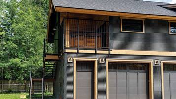 A two-story building with a balcony, large garage doors, and a wooden deck.