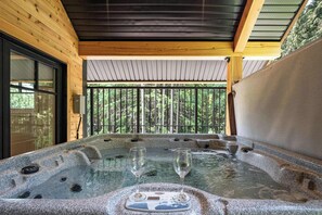 A hot tub with two glasses, surrounded by wooden walls and a view of trees. - The Cedar Suite - Secluded Mountain Retreat with Forest Views and Hot Tub (Revelstoke)