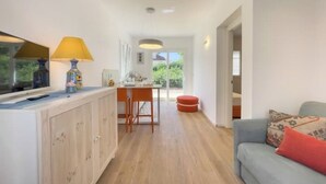Una sala de estar moderna con un sofá, un comedor con mesa y sillas, y una cocina con armarios y encimera.