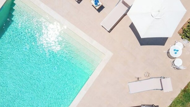 Zona de piscina en la azotea con sillones de descanso y sombrillas.