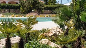Una piscina rodeada de palmeras y rocas, con un edificio al fondo.