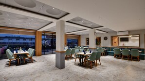Ein modernes Restaurant mit hohen Decken, großen Fenstern und verschiedenen Essbereichen.
