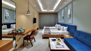 Ein Hotelzimmer mit Essbereich, zwei Betten, einer Couch, einem Schreibtisch und einem Spiegel.