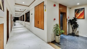 Ein Hotelgang mit Holztüren, einem Blumentopf und einem Gemälde an der Wand.