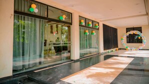 A modern hotel lobby with glass doors, a tiled floor, and a decorative archway. - Hotel Royal Celebration (Kawardha)