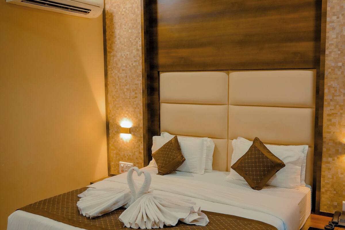 Ein Hotelzimmer mit einem großen Bett, einem Deckenventilator, einer Klimaanlage und einem Nachttisch mit Lampe.