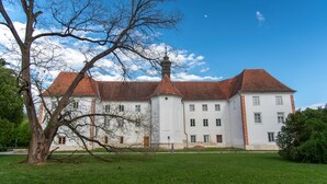 Um edifício grande e histórico, com fachada simétrica, diversas janelas e uma torre central imponente.