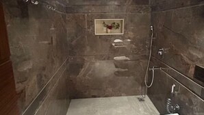 A modern bathroom with a marble floor, a white sink, and a shower area with a glass enclosure. - Eminence the Corbett (Ramnagar)