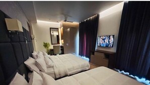 A hotel room with two beds, a TV, a desk, and a chair. - Eminence the Corbett (Ramnagar)