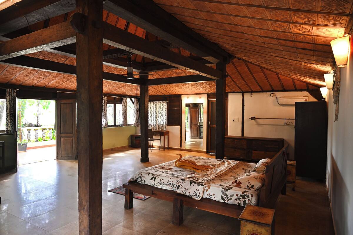 A spacious room with a wooden ceiling and a bed with floral bedding.