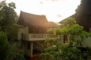 A traditional wooden house with a balcony, surrounded by lush greenery and a staircase leading to the upper level. - Sohum Spiritual Resort (Arambol)