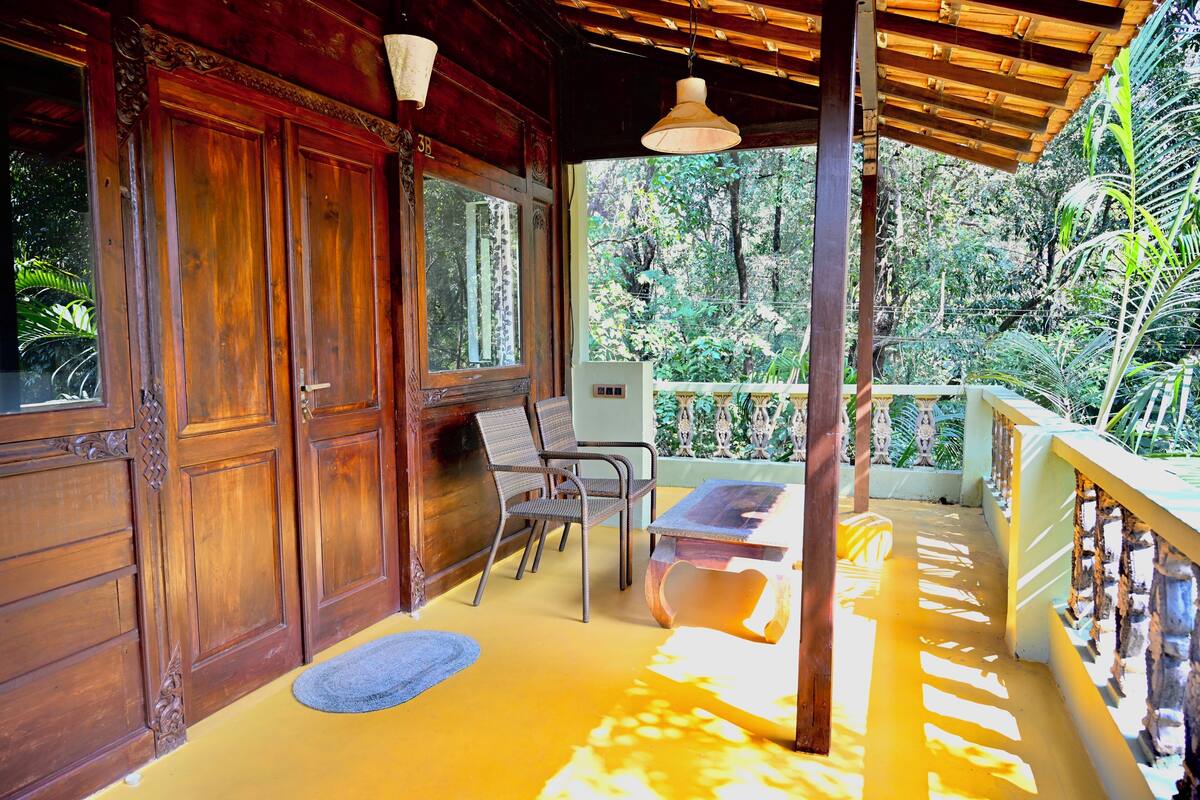 A wooden door with intricate carvings, a bench, and a table under a wooden pergola.