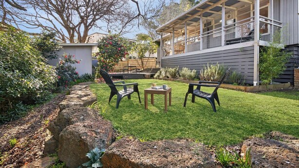 A residential property with a covered outdoor seating area, a well-maintained lawn, and a variety of plants. - Nella (Lorne)