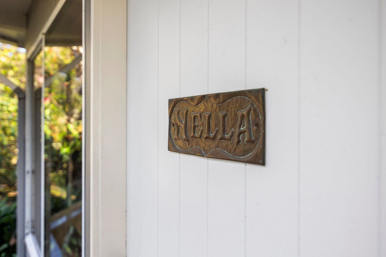 A metal sign with the word 'NELLAS' mounted on a white wall.