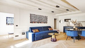 Una sala de estar moderna con un sofá azul, una mesa de centro redonda y un comedor con sillas azules.