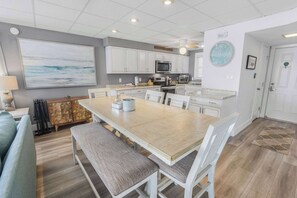 Une cuisine moderne avec des meubles blancs, un grand îlot central et un coin repas équipé d’une banquette.