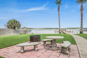 A patio area with stone tables and benches, a fire pit, and a view of a lake with a wooden dock.
