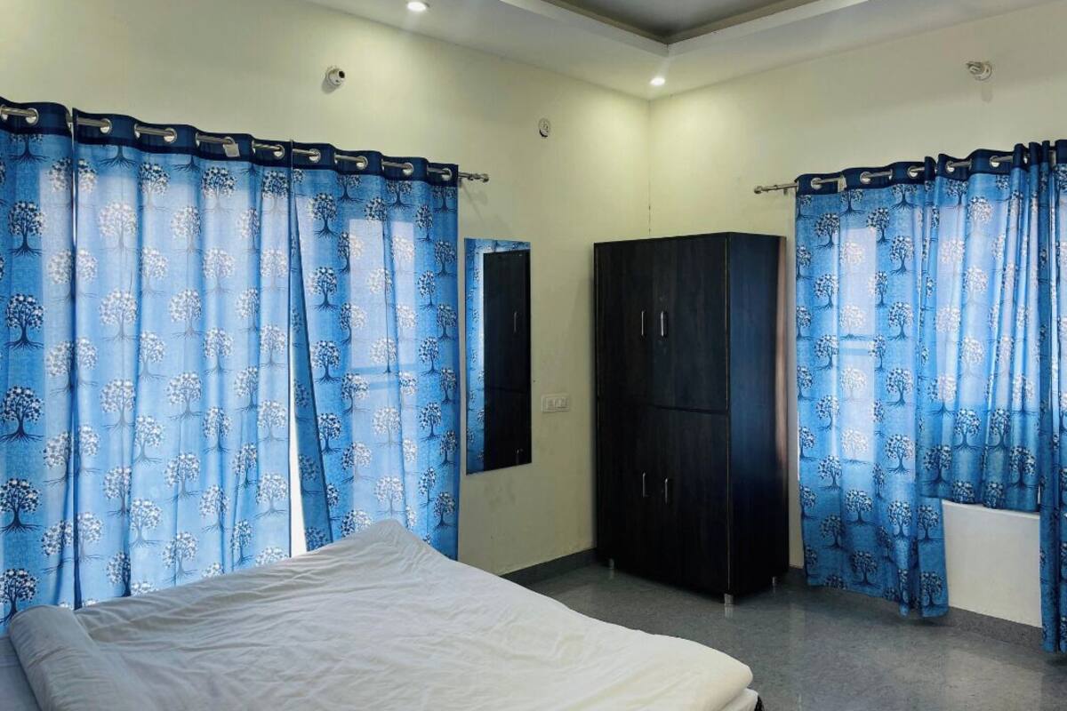 A bedroom with a bed, two wardrobes, and curtains with a tree pattern.