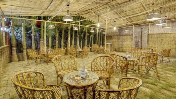 An indoor bamboo structure with wicker furniture and hanging lights. - Parinay Vatika Banquet & Party Lawn (Haldwani)
