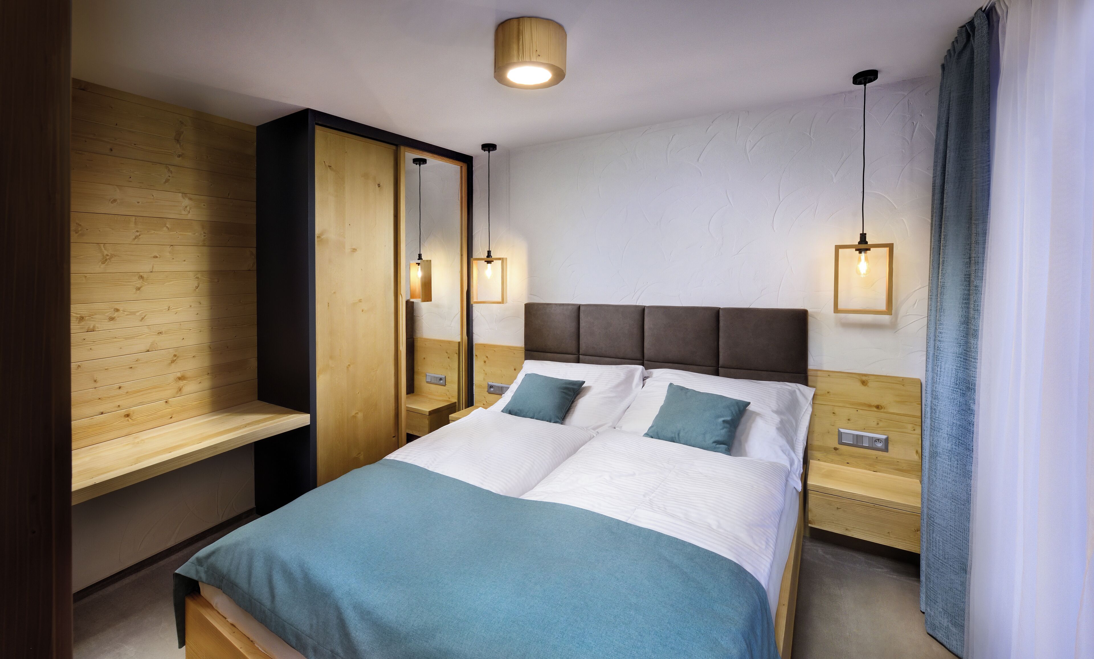 A modern hotel room with a large bed, wooden headboard, and a built-in wardrobe.