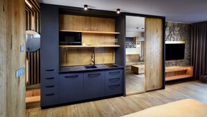 A modern kitchen with wooden shelves, a microwave, and a sink. - APLEND Monte Móry (Štrba)
