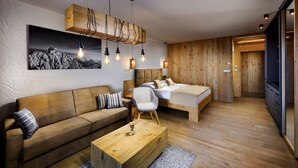 A modern hotel room with a wooden floor, a sofa, a bed, and a coffee table. - APLEND Monte Móry (Štrba)