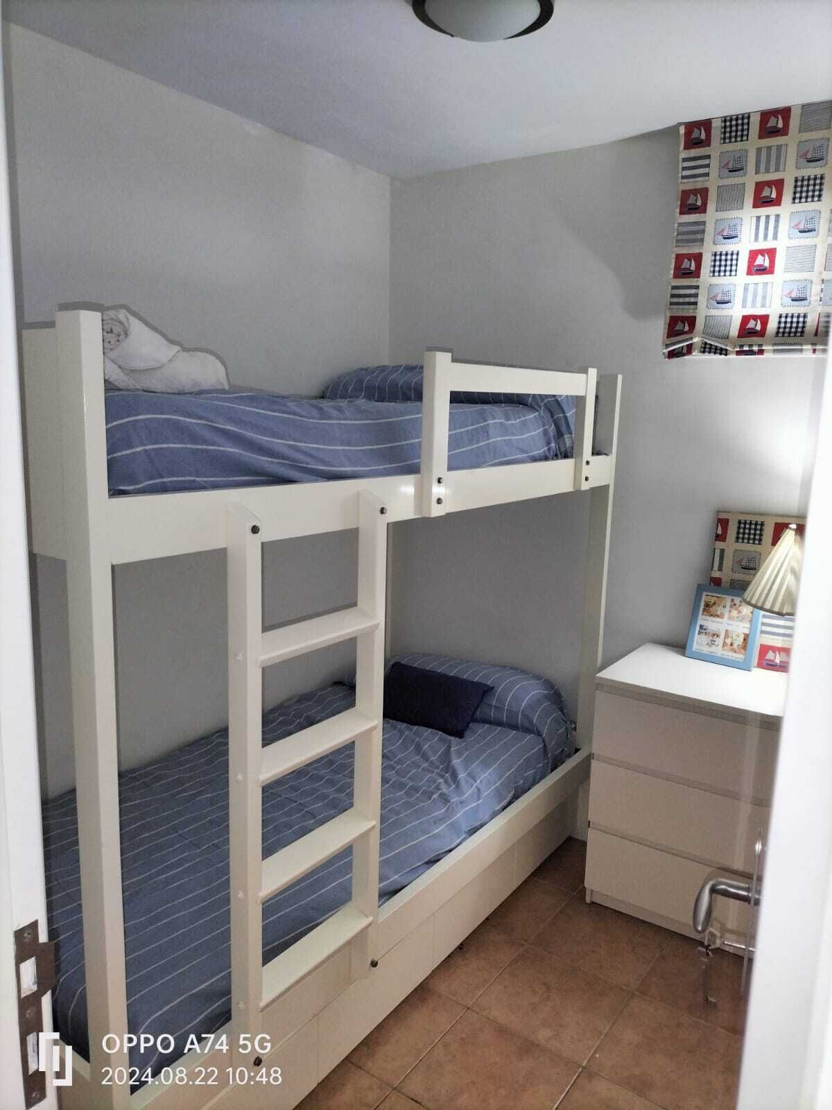 Habitación con literas, un escritorio pequeño y una pared decorada con motivos náuticos.