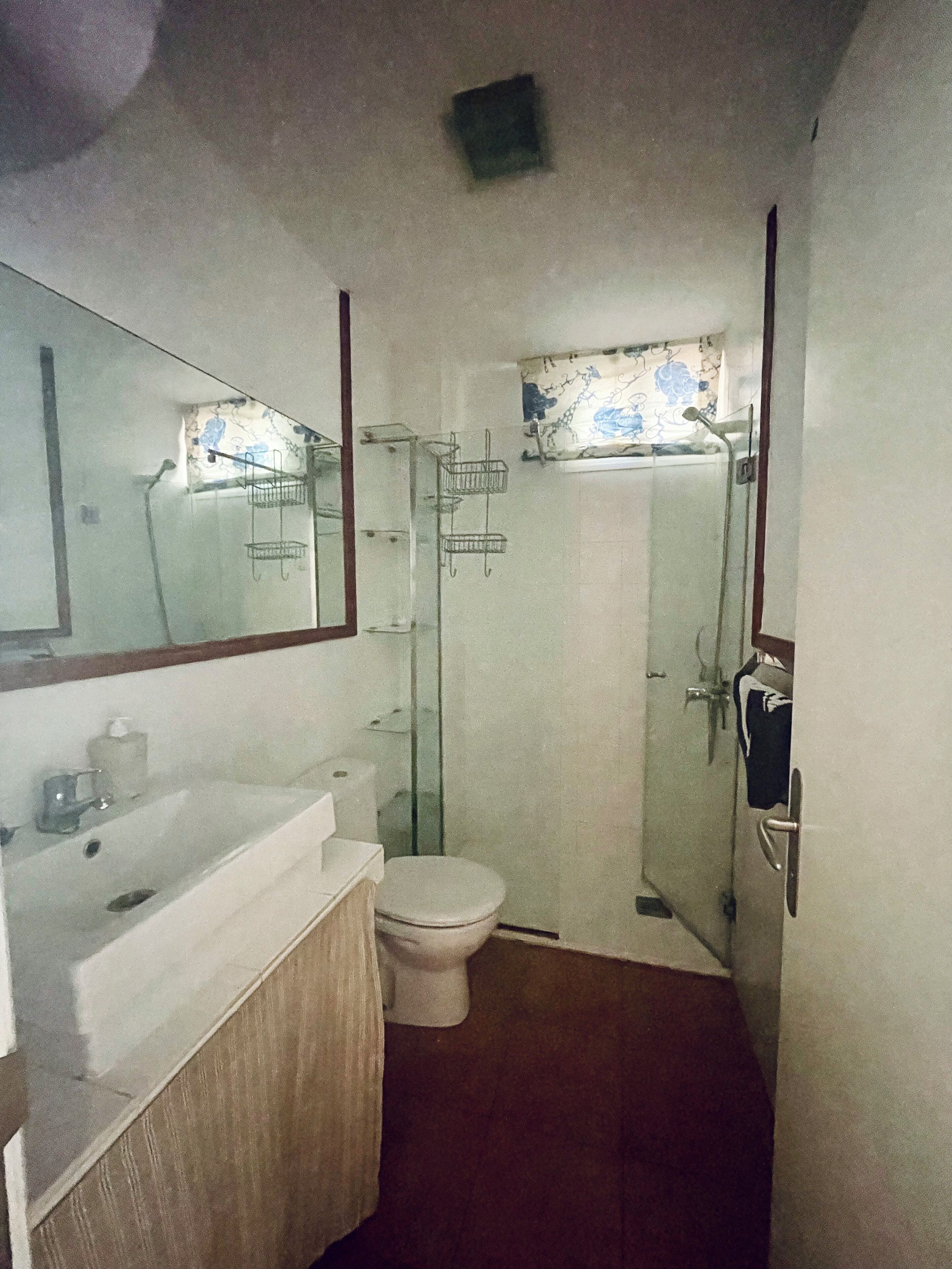 A small bathroom with a toilet, sink, and shower.