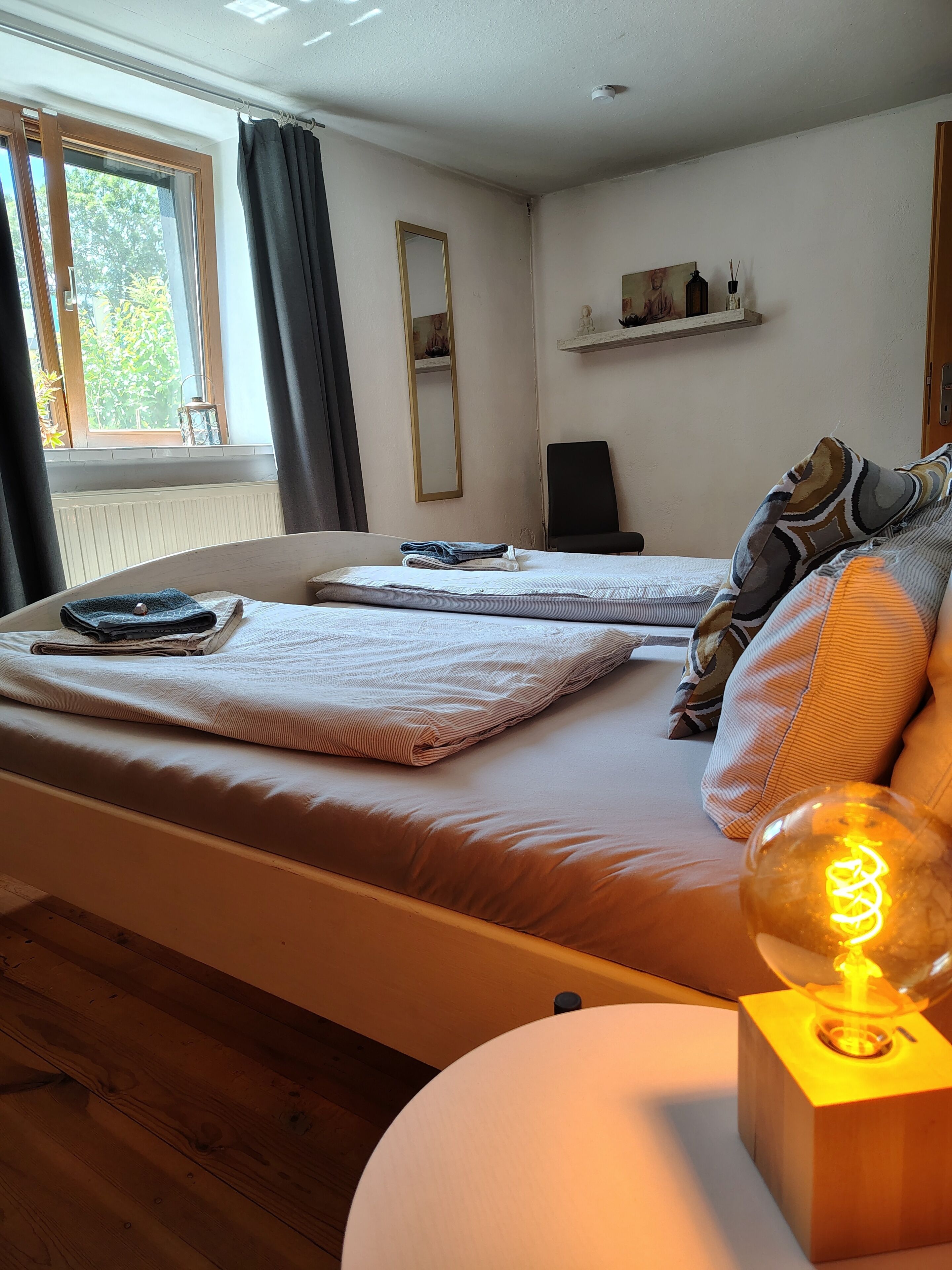 Une chambre à coucher avec un lit, une chaise, une lampe et une fenêtre.