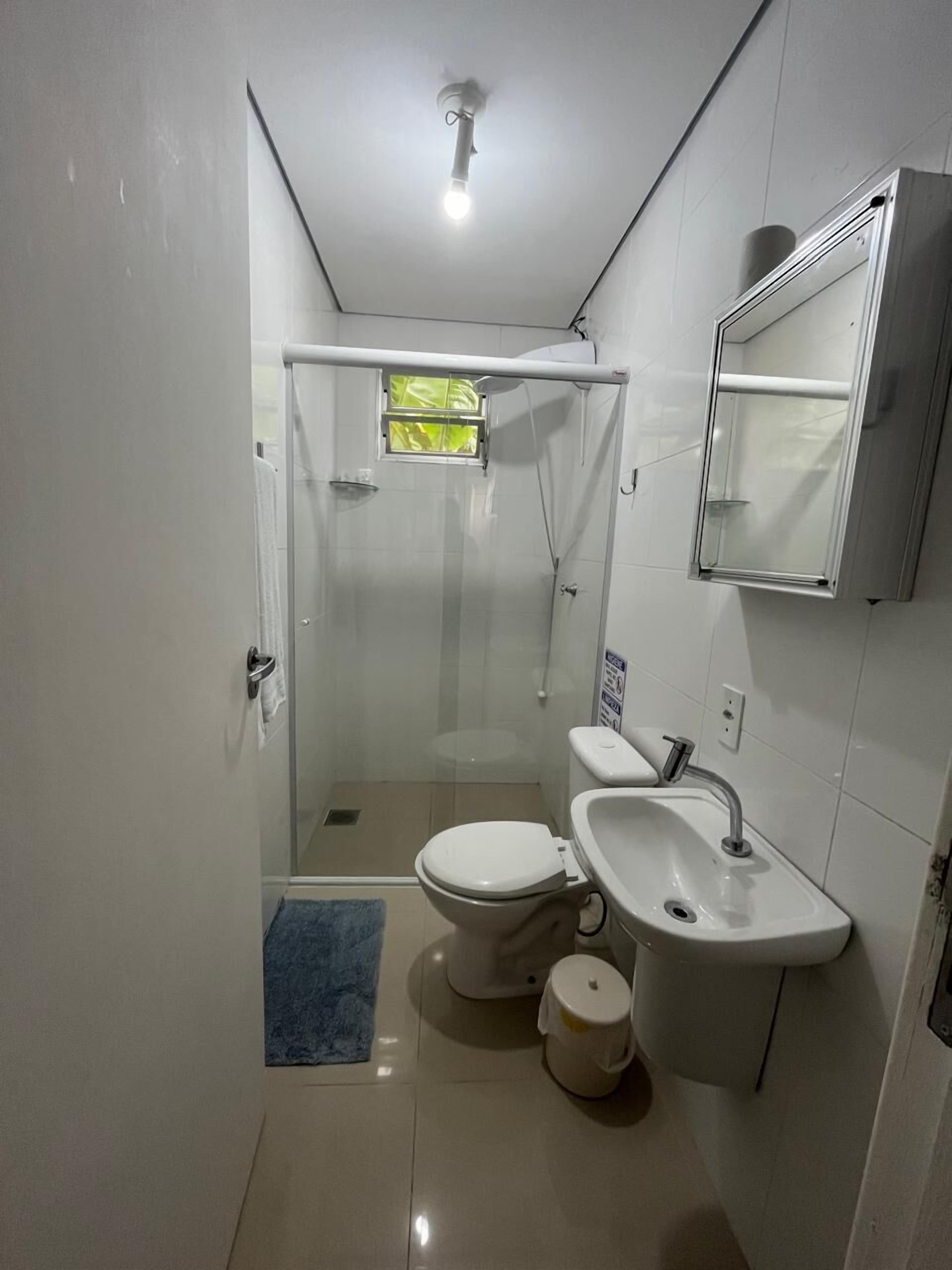 Un baño pequeño con inodoro, lavamanos y ducha.