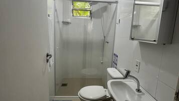 Un baño pequeño con inodoro, lavamanos y ducha.