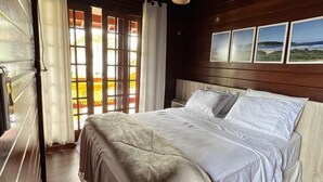 A bedroom with a wooden ceiling, a bed with white bedding, and a window with curtains. - Pousada Recanto do Neca (Florianópolis)