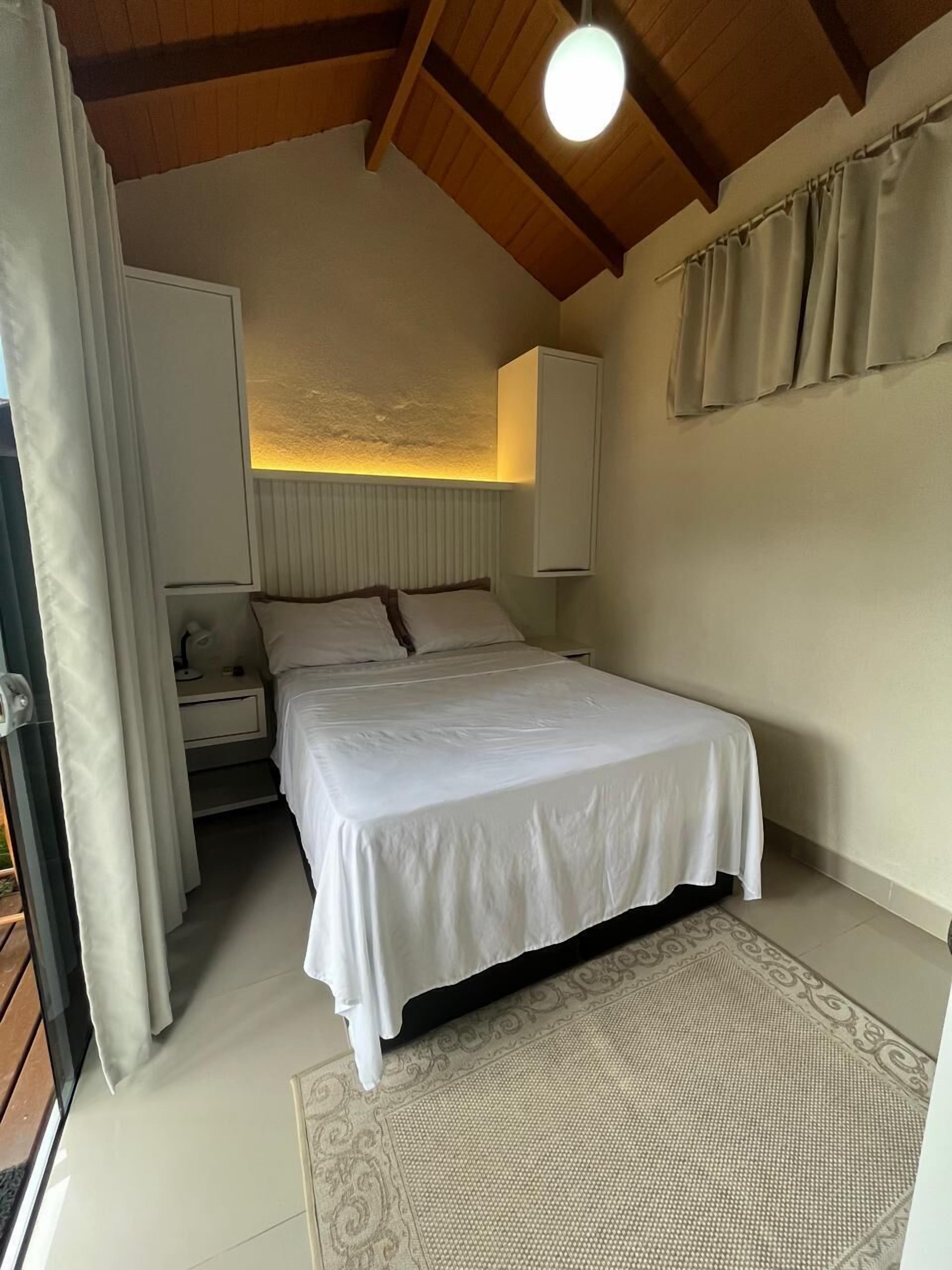 Ein Schlafzimmer mit Bett, Nachttisch, Lampe und Deckenleuchte.