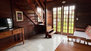 A wooden interior with a staircase, a TV, a sofa, and a dining table. - Pousada Recanto do Neca (Florianópolis)