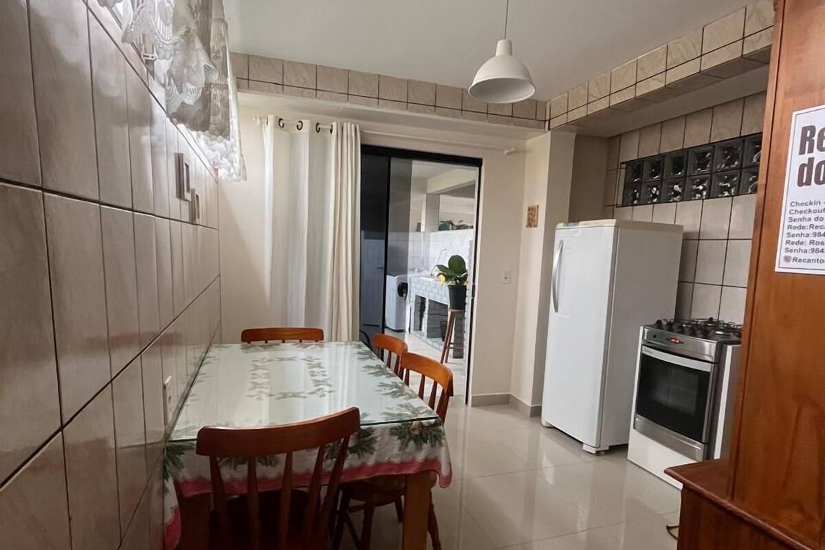 A kitchen with a dining table, chairs, a refrigerator, and an oven.